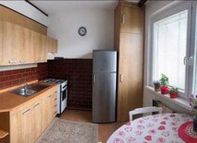 A kitchen in a 3-room apartment with a kitchen unit, a gas stove, and a floor with a wooden decor.
