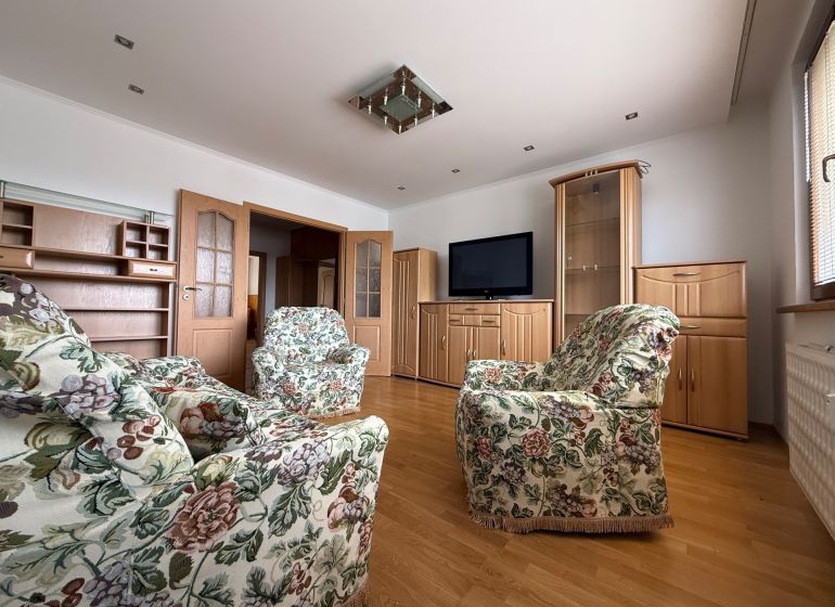 Living room in a 4-room apartment with a wooden decor floor and floral furniture.