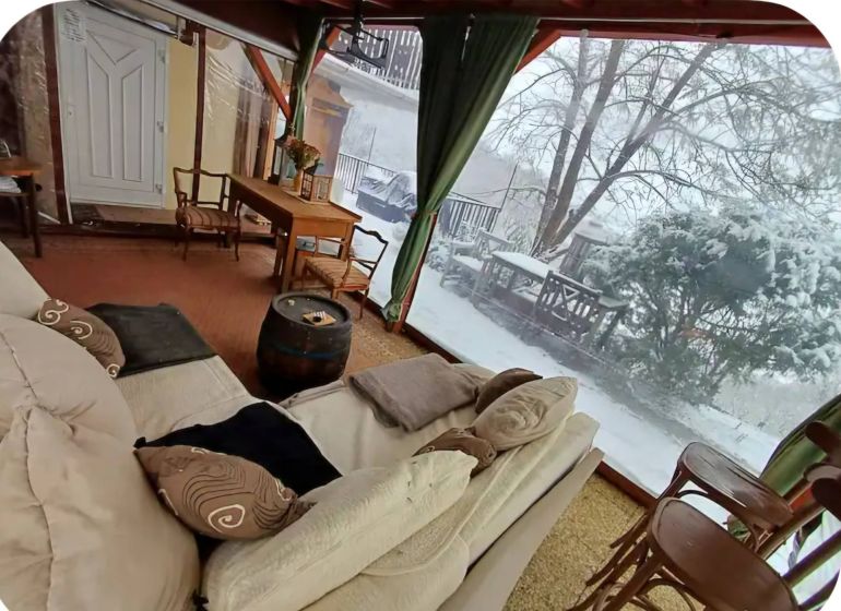 Winter garden with a sofa, table, and chairs in a family house.