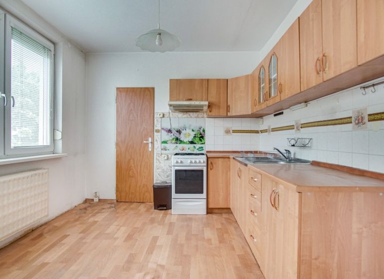 A kitchen in a 3-room apartment with a wooden decor floor and a white gas stove.