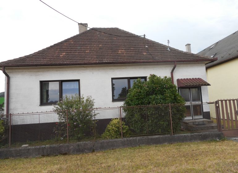 A family house in Trenčín with a white facade, a garden, and a sloped roof.