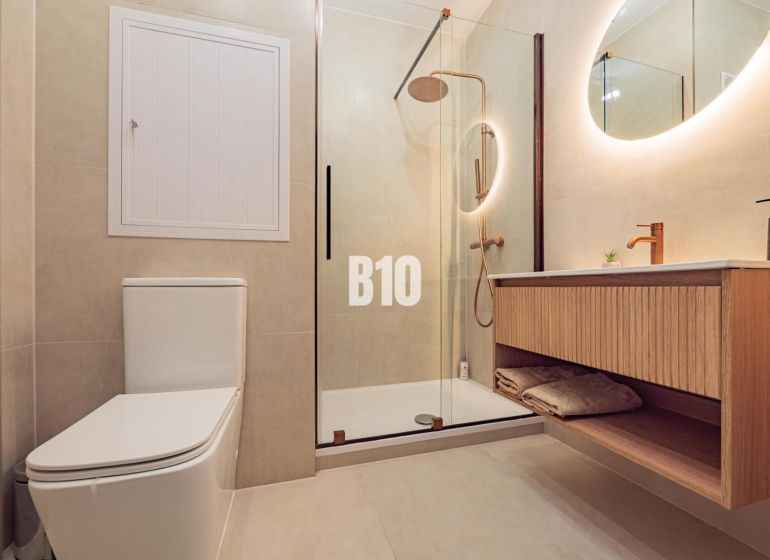 Bathroom with toilet, wooden sink, and shower in a studio apartment.