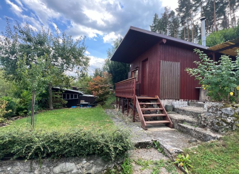 A wooden cabin surrounded by greenery in the Gardens near Ružomberok with stone-clad steps.