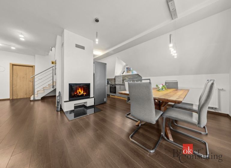 Dining area with a table, chairs, and a fireplace, floor with wood decor.