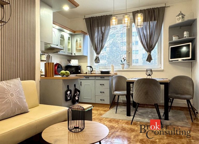 A kitchen in a 3-room apartment with stylish lighting fixtures and a wooden decor floor.