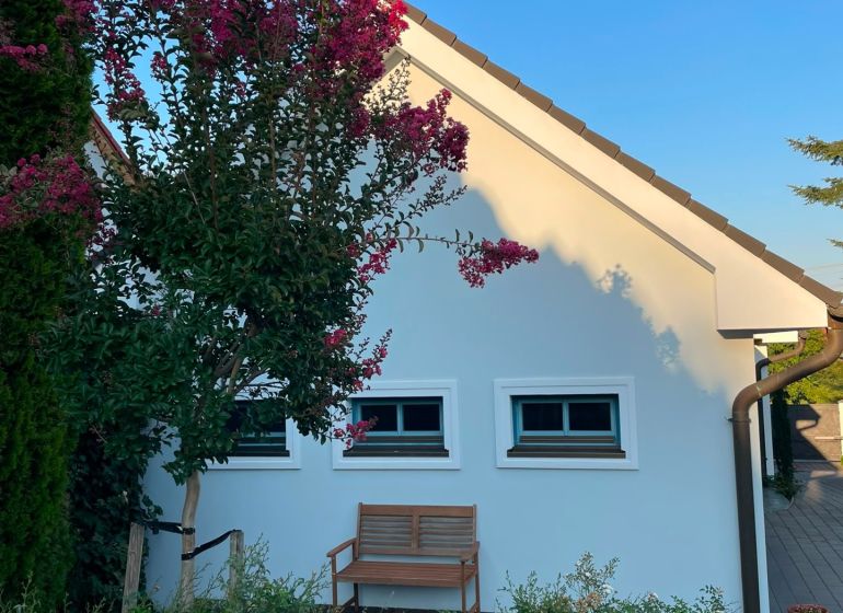 A family house in Bratislava - Dúbravka with a bench and flowers in front of it.