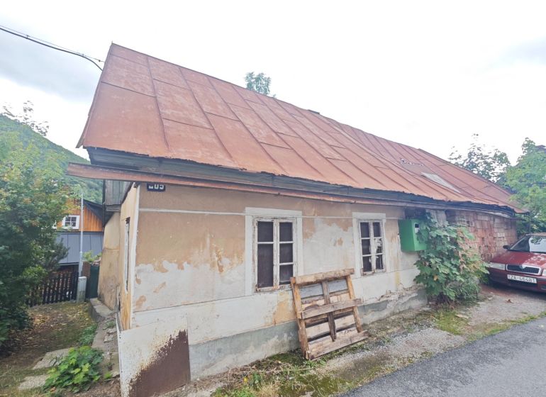 A family house in Špania Dolina with visible plaster and a metal roof.