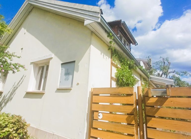 A family house in Rožňava with a fence and greenery, clear sky in the background.