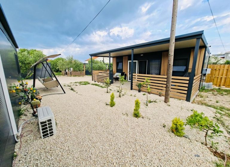 A recreational apartment in Sukošan with a terrace, gravel yard, and a swing bench.