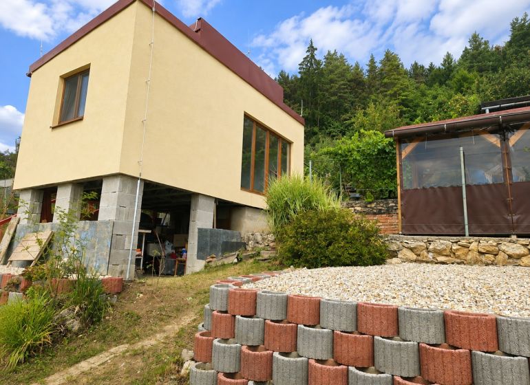 A cottage on Tulská Street in Banská Bystrica surrounded by greenery and stones.