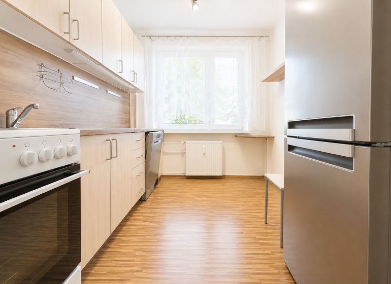A kitchen in a 3-room apartment with a wooden decor, stove, and refrigerator.