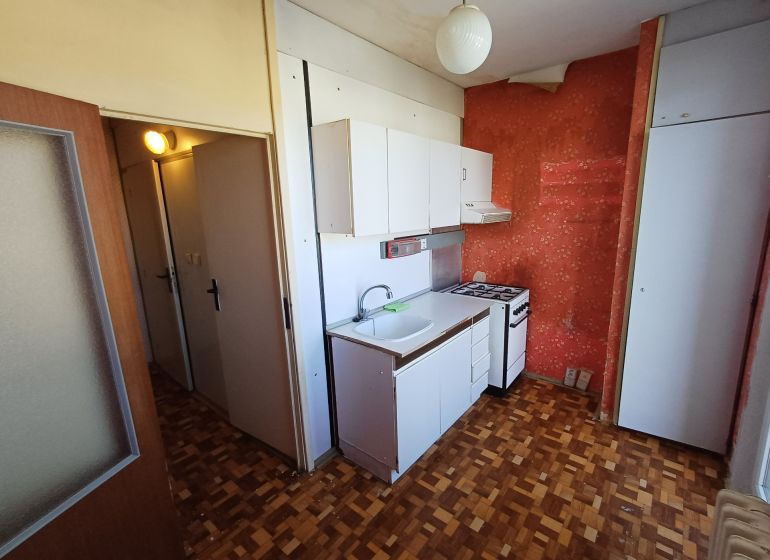 Compact kitchen in a studio apartment with a wooden decor floor and a simple kitchenette.