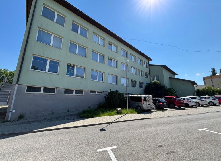 The exterior of offices in Kežmarok with parked cars on a sunny street.