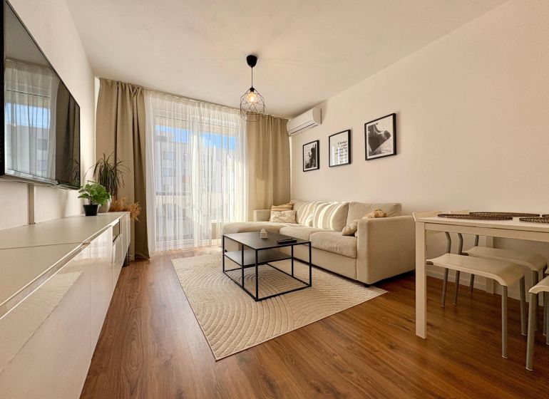 Living room with a sofa and TV, floor with wood decor in a 2-room apartment.