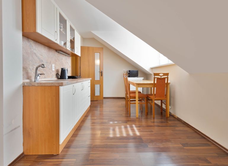 A kitchen with a slope, a dining table, and a wooden decor floor in a 2-room apartment.
