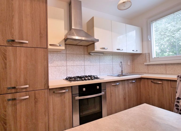 A kitchen in a 3-room apartment with wooden cabinets and a stove.