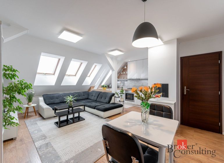 Living area of a 3-room apartment with a sofa, table, and wooden decor flooring.