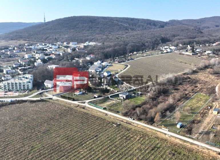 Aerial view of vineyards and houses in the Záhrad area in Bratislava III, surrounded by hills.