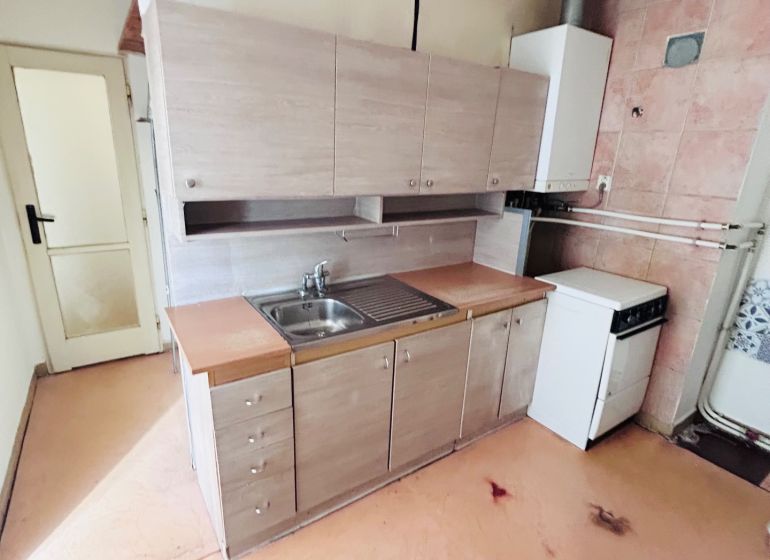A kitchen in a 2-room apartment with a simple kitchenette and a floor with a wood decor.