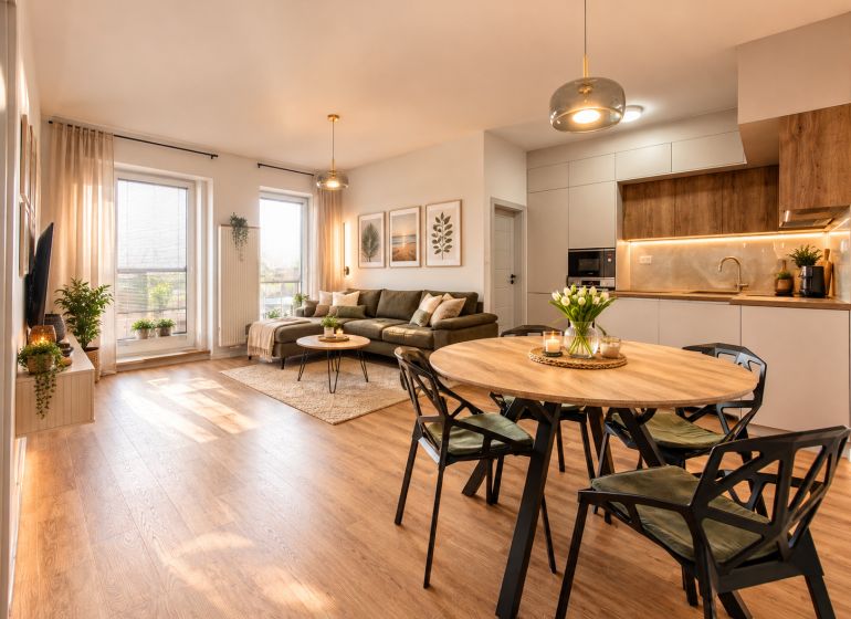 Living room and kitchen in a 4-room apartment with a wooden decor floor, comfortable seating, and decorations.