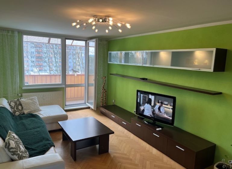 A living room in a 3-room apartment with a wooden decor floor and green walls.