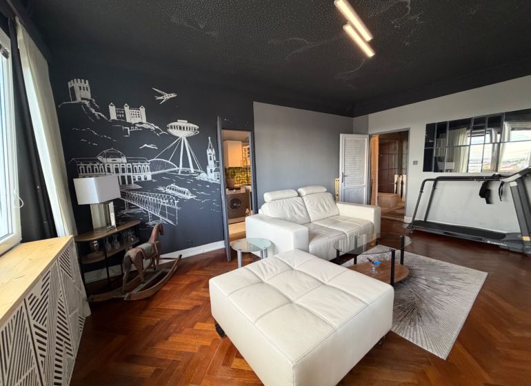 Living room with a sofa, tapestry, treadmill, and wooden decor flooring in a 4-room apartment.