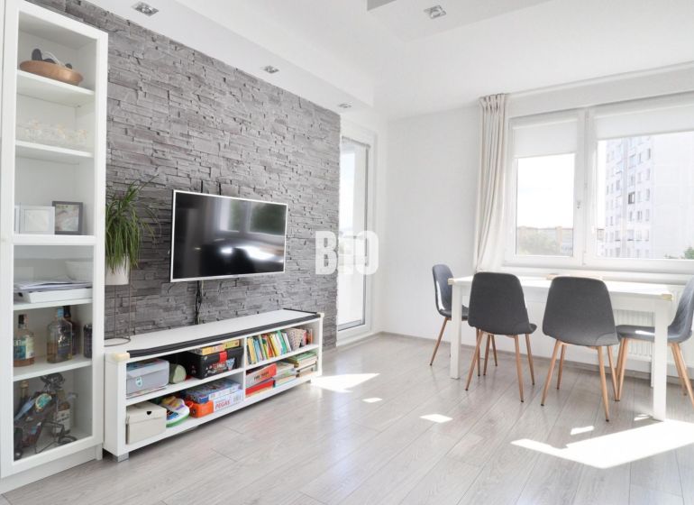 Living room in a 3-room apartment with brick cladding and a wooden decor floor.
