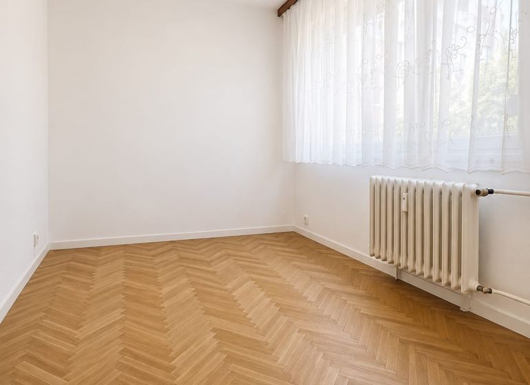 A room in a 3-room apartment with a wooden decor floor and a radiator.