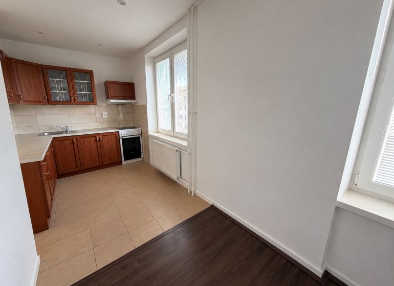 A kitchen in a 2-room apartment with wooden decor and tiled flooring.