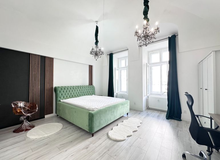 Bedroom in a 3-room apartment with a green bed and chandeliers, floor with wooden decor.
