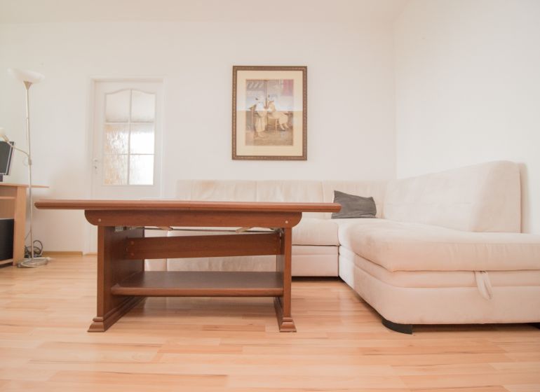 Living room with a corner sofa, table, and floor with wood decor in a 3-room apartment.
