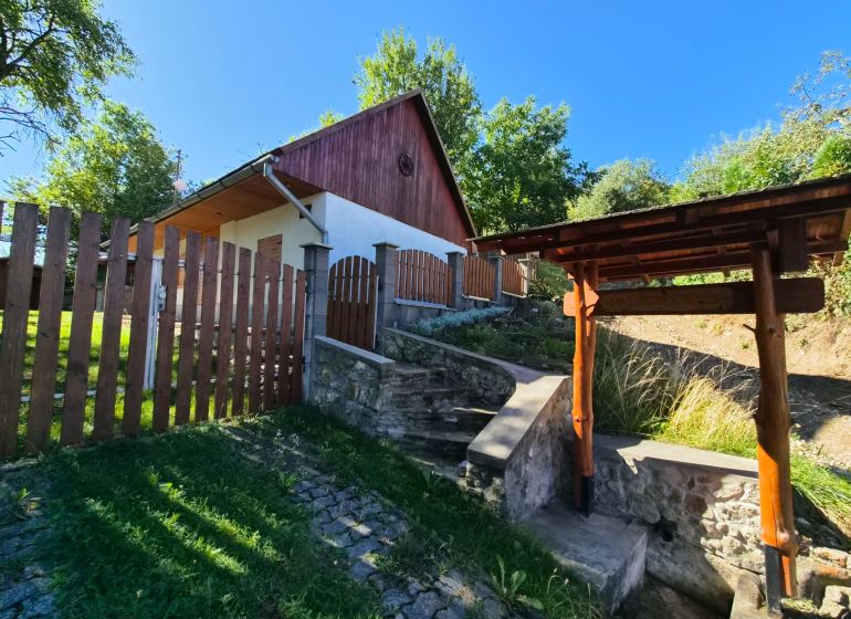 A family house in Mikušovce with a wooden fence and a stone staircase.