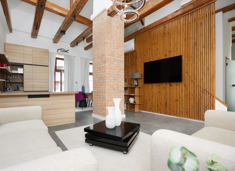 A living room with a brick wall, wooden decor flooring, and comfortable armchairs in a three-room apartment.