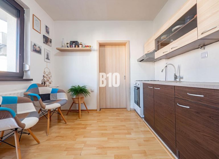 A kitchen in a one-room apartment with a wooden decor floor and modern furniture.