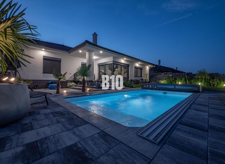 A family house in Nitra with a swimming pool and garden seating in an evening atmosphere.