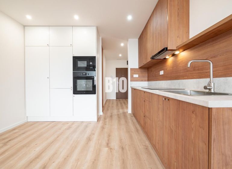 A kitchen in a 3-room apartment with white cabinets and a wood-patterned floor.