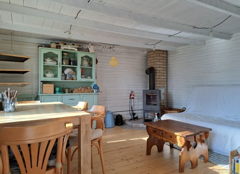 The interior of the cottage with a wood-patterned floor, wooden furniture, and a stove.