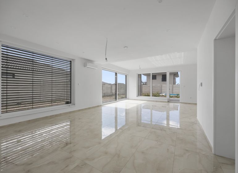 Spacious living area in a family house with large windows and glossy tiles.