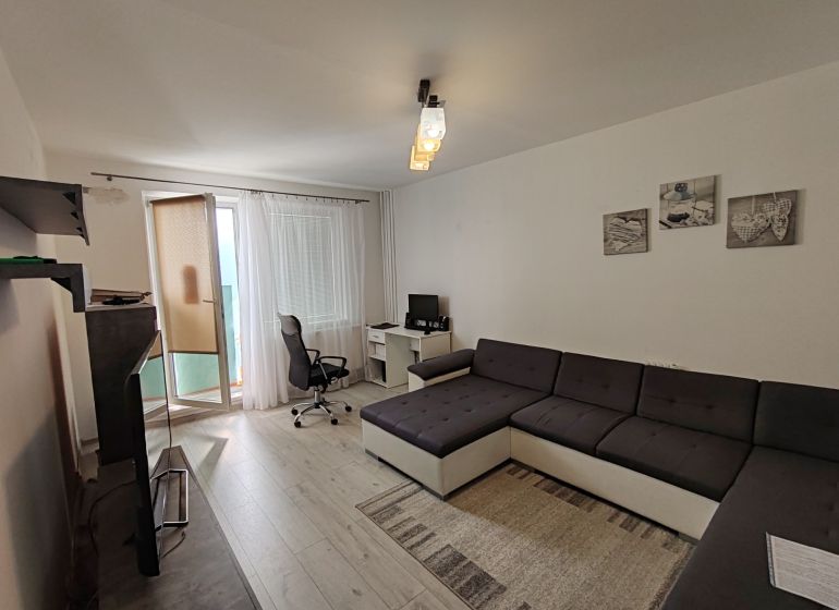 Living room in a 3-room apartment with a wooden decor floor, workspace, and a sofa.