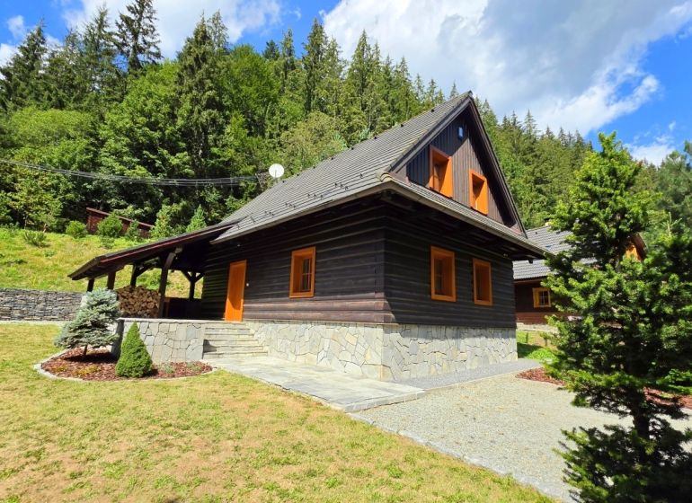 In the Jarabe, there is a cabin surrounded by forest, with wooden cladding and a stone foundation.