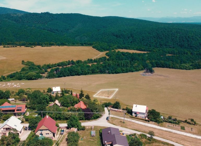 A rural view of residential plots in Podhradie surrounded by forests and meadows.