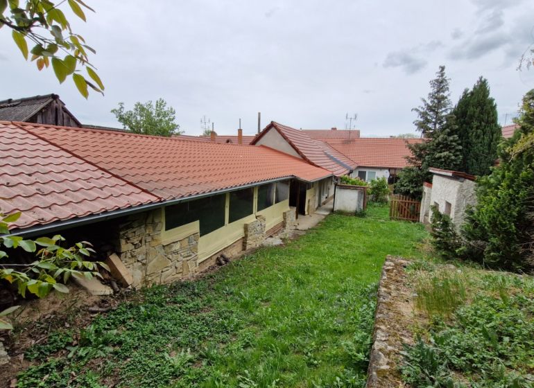A garden at a family house in Mokré Háj with a stone wall and red roofing.
