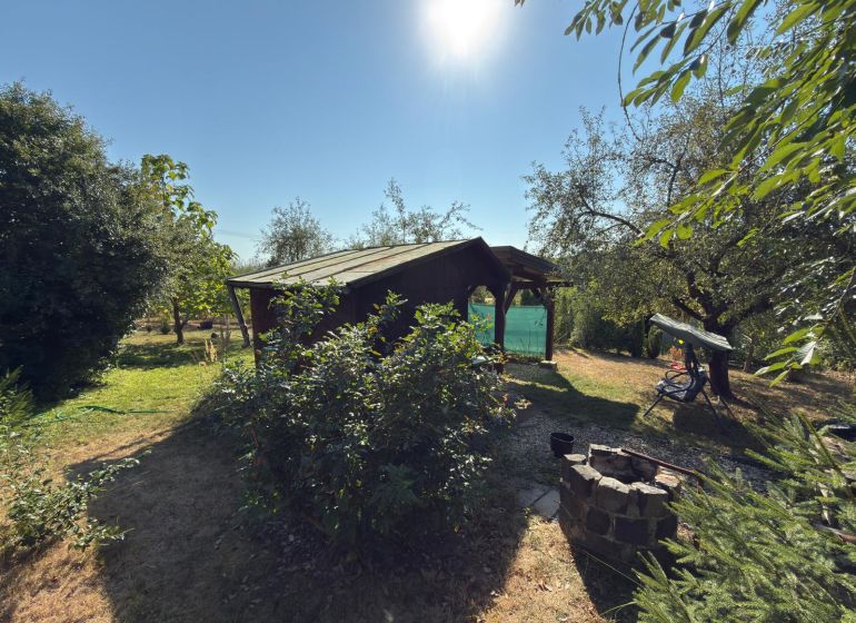Cottage on the Vineyard in Lučenec surrounded by greenery and trees, with a fire pit in the garden.