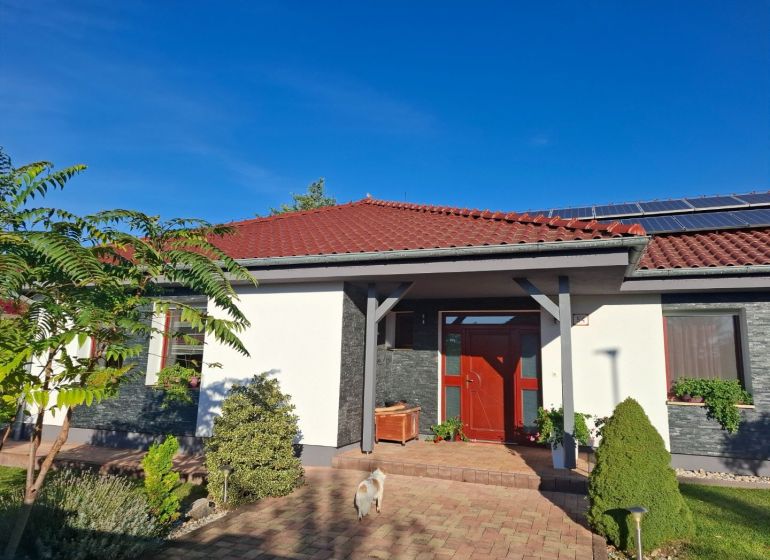 A family house in Nové Zámky with a red roof, solar panels, and a garden.