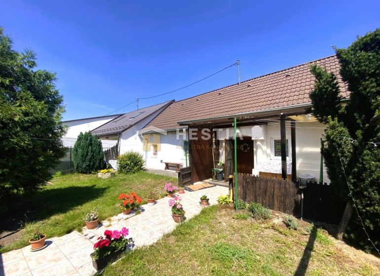 A family house in Borský Mikuláš with a garden, flowers, and a lawn in a sunny yard.