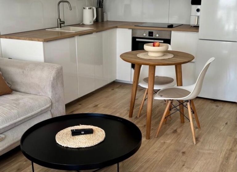 A kitchen corner with a round table and a floor with a wooden decor in a 2-room apartment.
