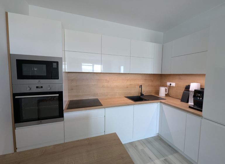 A kitchen in a 2-room apartment with a wooden decor floor and modern appliances.