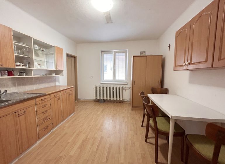 A kitchen in a family house with a wooden decor floor, wooden cabinets, and a dining table.