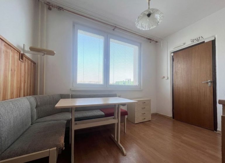 Dining area with seating and a wooden-patterned floor in a 2-room apartment.