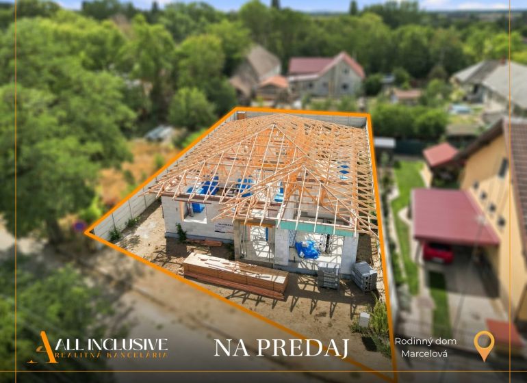 A family house under construction in Marcelová with a completed wooden roof structure.